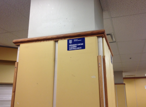 A sign reading "premises under camera surveillance" is located on a pillar in the entrance of the Library Building. (Jessica Lepore/The Ryersonian)