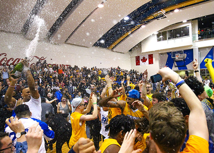Ryerson players and fans celebrate after the men's basketball team defeated the Carleton Ravens 73-68 to capture the Wilson Cup, the first OUA Championship in school history. This photo, taken on March 12, 2016, was awarded the 2015-2016 OUA Photo of the Year. (Courtesy Alex D'Addese)