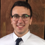 Man with glasses and tie smiling at camera