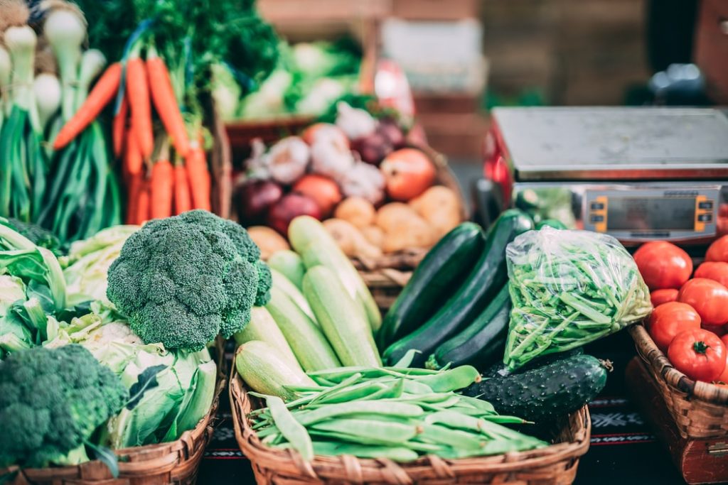 A variety of green vegetables like broccoli, cucumbers and edamame in boxes up close