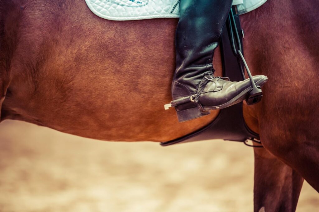 a closeup shot of someone's boot while they are on a horse in a saddle