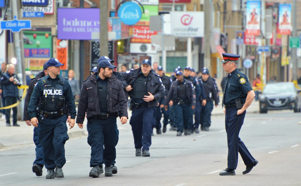 a group of policemen walk on an empty street that's been cleared of pedestrians and cars after a van drives into a crowd in Toronto